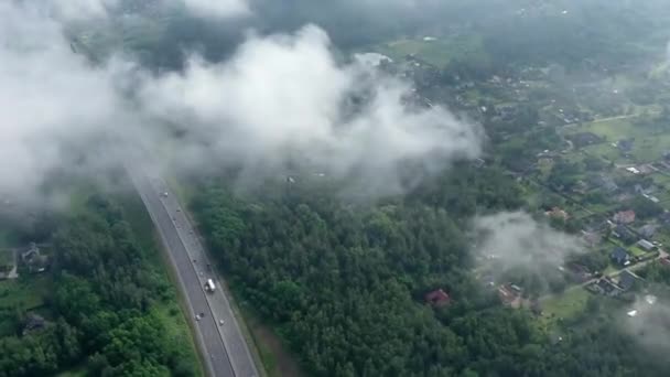 Hyperlapse πάνω Χαμηλή πρωί αφράτα σύννεφα πάνω από ένα μεγάλο αυτοκινητόδρομο που τρέχει μέσα από το δάσος. Μια κινηματογραφική πτήση ενός τηλεκατευθυνόμενου μέσα από τα σύννεφα. — Αρχείο Βίντεο