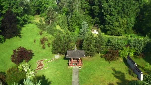 Casa coreana con pasarela en el jardín entre los árboles. Una extraña casa en la azotea en el jardín de la cultura surcoreana. Pagoda en el diseño paisajístico del parque . — Vídeos de Stock