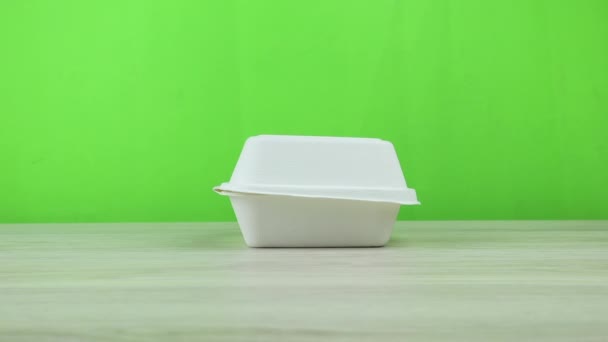Aprire un contenitore di cartone su fondo verde. Un uomo apre un contenitore di cartone usa e getta eco food su uno sfondo verde. — Video Stock