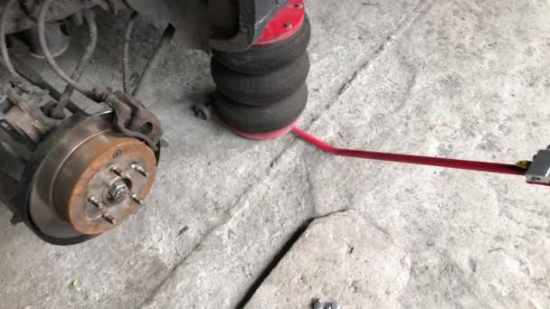 Panorama de la estación de servicio del coche: gato neumático, disco de freno trasero con pastillas de freno — Vídeo de stock