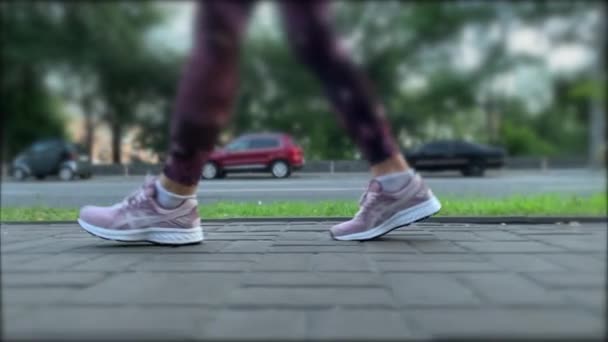 Pasos de una mujer en zapatos deportivos púrpura en baldosas de pavimentación. Dolly Shot. — Vídeo de stock