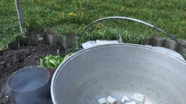 Reuzel wordt gebakken in een gietijzeren pot boven een vuur buiten — Stockvideo