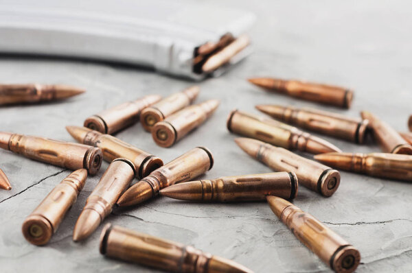 Silver full magazine for assault rifle and scattered bullets on old grey broken concrete