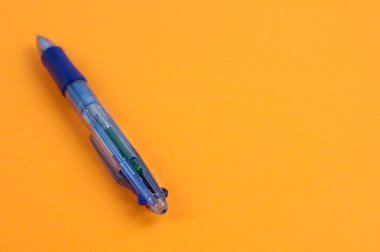 Bir mavi şeffaf multi renk tükenmez arka plan kopya alanı ile turuncu kağıt üzerinde