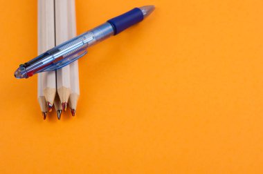 Multi renk mavi şeffaf tükenmez ve yığın portakal Kağıt kopya alanı ile arka plan üzerinde ahşap kalemler