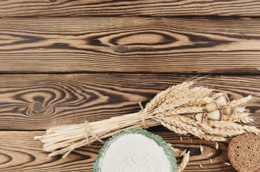 Eski rustik ahşap kalaslar üzerinde cam kase buğday ve haşhaş ve dağınık tahıl ve ekmek ve un dilim bir demet