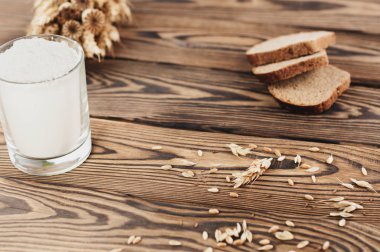 Buğday ve haşhaş bir demet ve dağınık tahıl ve eski rustik ahşap kalas üzerinde cam ekmek ve un üç dilim çok