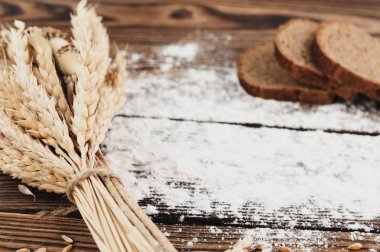 Eski rustik ahşap kalaslar üzerinde buğday ve haşhaş ve serpiştirilmiş un ve ekmek üç dilim bir demet