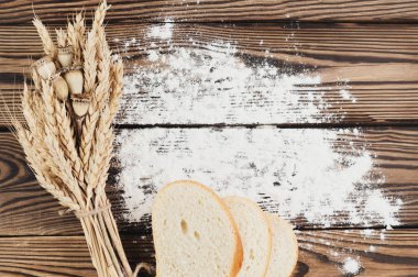 Eski rustik ahşap kalaslar üzerinde buğday ve haşhaş ve serpiştirilmiş un ve ekmek dilimleri bir demet