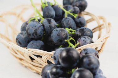 Eski ahşap rustik beyaz kalaslar taze olgun mavi üzüm tam hasır sepet