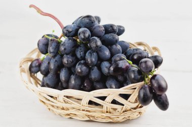 Eski ahşap rustik beyaz kalaslar taze olgun mavi üzüm tam hasır sepet