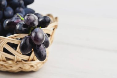 Eski ahşap rustik beyaz kalaslar taze olgun mavi üzüm tam hasır sepet