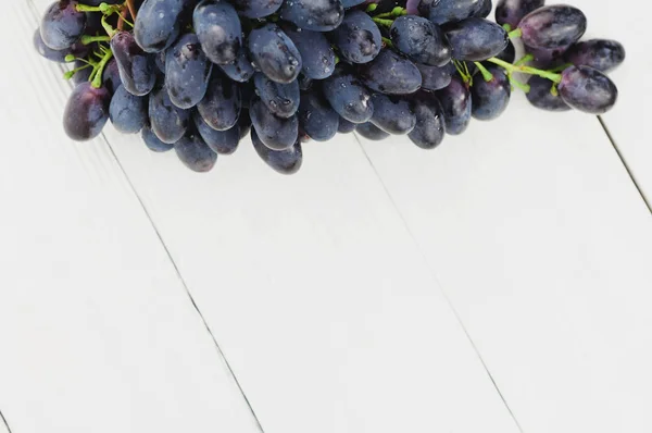 一串新鲜成熟的蓝色葡萄在古老的木制质朴的白色木板上 — 图库照片