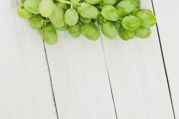 古い木製の素朴な白い板に新鮮な熟した緑のブドウの束 — ストック写真