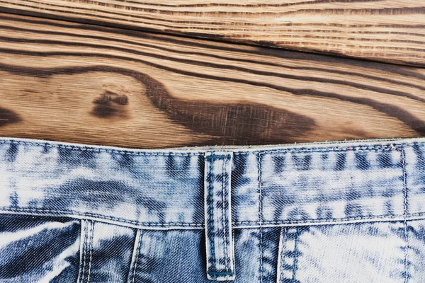 古い木製の素朴な茶色のテーブルに新しい青いジーンズ — ストック写真