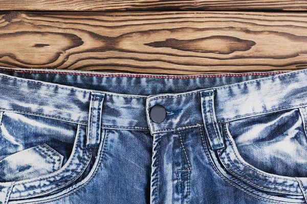 古い素朴な木製の茶色の板に新しい青いジーンズの前面空のポケット — ストック写真