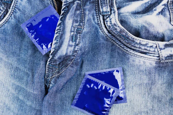 ジッパーにコンドーム1個 青いジーンズに2個のコンドームが散らばっている — ストック写真