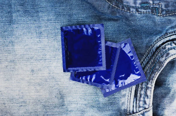 Три Презервативи Упаковці Фольги Синього Кольору Розкидані Блакитних Нових Джинсах — стокове фото