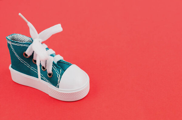 Одна новая зеленая спортивная обувь на красной бумаге
