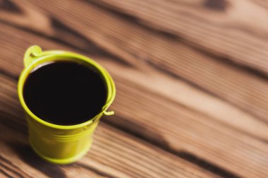 Kopya alanı ile eski yıpranmış ahşap masa üzerinde siyah kahve tam yeşil kova