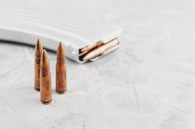 Saldırı tüfeği ve eski gri kırık beton üzerinde üç mermi için Gümüş tam dergi