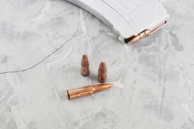 Saldırı tüfeği ve eski gri kırık beton üzerinde üç mermi için Gümüş tam dergi