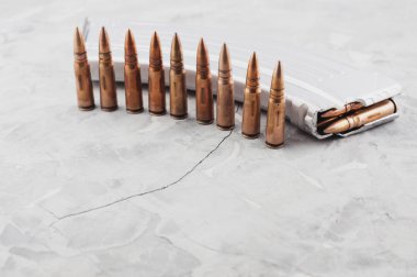 Eski gri kırık beton üzerinde saldırı tüfeği ve mermi satır için Gümüş tam dergi