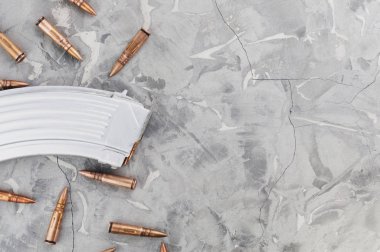 Saldırı tüfeği ve eski gri kırık beton üzerinde birçok dağınık mermi için Gümüş tam dergi