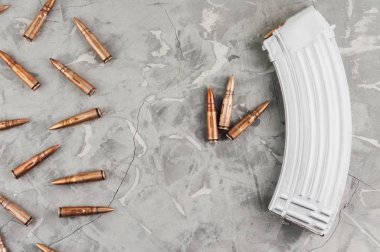 Saldırı tüfeği ve eski gri kırık beton üzerinde birçok dağınık mermi için Gümüş tam dergi