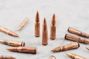 Eski gri kırık beton üzerinde saldırı tüfeği için üç metal mermi ve birçok dağınık mermi