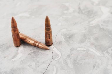 Eski gri kırık beton üzerinde saldırı tüfeği için üç metal mermi