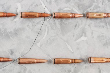 Eski gri kırık beton üzerinde saldırı tüfeği için metal mermi iki satır