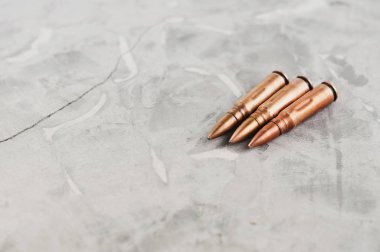 Eski gri kırık beton üzerinde saldırı tüfeği için üç metal mermi