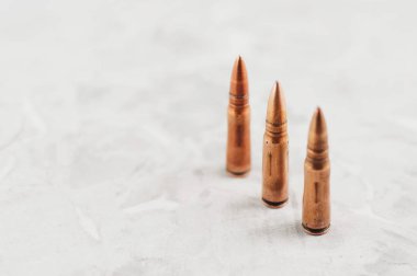 Eski gri kırık beton üzerinde saldırı tüfeği için üç metal mermi Satır