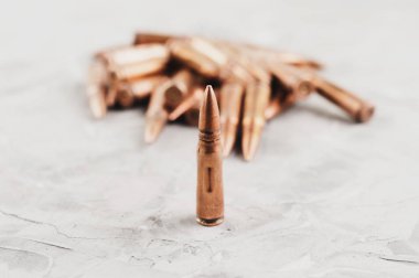 Eski gri kırık beton üzerinde saldırı tüfeği için metal mermi ve tek mermi yığını