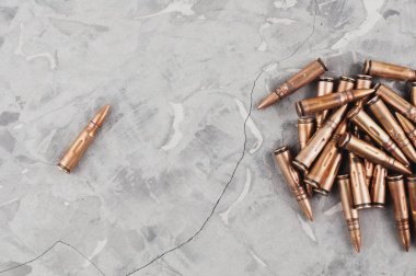 Eski gri kırık beton üzerinde saldırı tüfeği için metal mermi ve tek mermi yığını