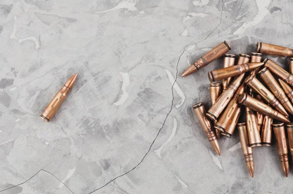 Eski gri kırık beton üzerinde saldırı tüfeği için metal mermi ve tek mermi yığını