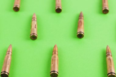Yeşil arka plan üzerinde saldırı tüfeği için birçok metal mermi Satır
