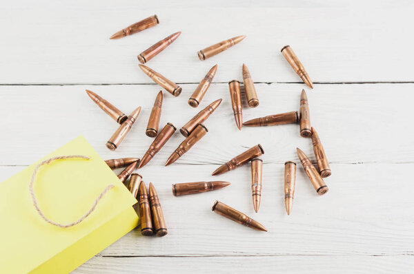 Scattered from a yellow paper packet of a bullets on old rustic white wooden planks