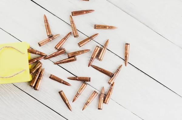 Scattered from a yellow paper packet of a bullets on old rustic white wooden planks