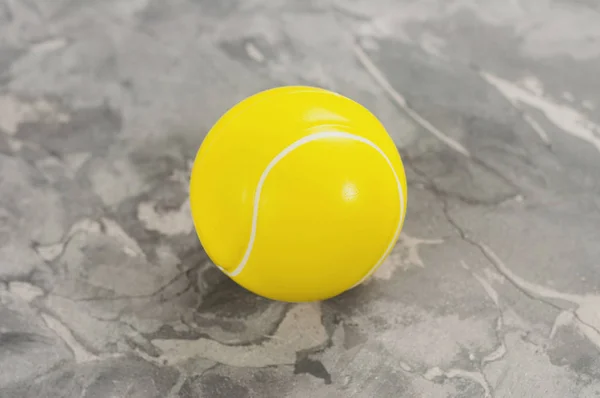 One new yellow soft rubber tennis ball on old worn cement