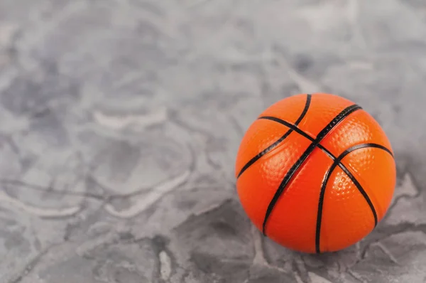 One new orange soft rubber basketball ball on old worn cement