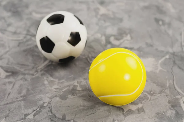 Two new soft rubber soccer and tennis balls on old worn cement