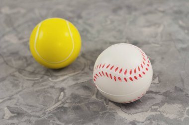Eski yıpranmış çimento üzerinde iki yeni yumuşak kauçuk tenis ve beyzbol topları
