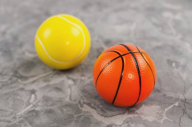 Eski yıpranmış çimento üzerinde iki yeni yumuşak kauçuk tenis ve basketbol topları