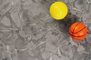 Eski yıpranmış çimento üzerinde iki yeni yumuşak kauçuk tenis ve basketbol topları. Üstte görüntü