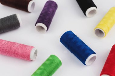 Beyaz arka planda yeni renkli dikiş ipliklerinin dağınık bobinleri