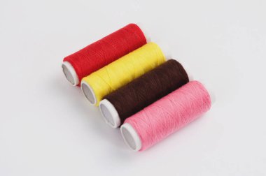 Beyaz arka planda yeni renkli dikiş iplikleri dört bobinler