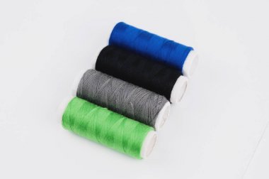 Beyaz arka planda yeni renkli dikiş iplikleri dört bobinler