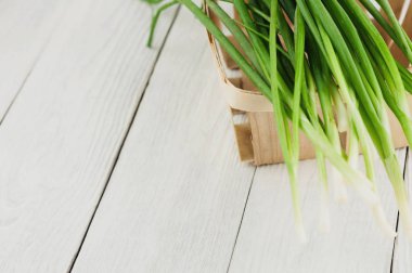 Eski beyaz rustik ahşap masa üzerinde hasır sepet yeşil taze soğan bir sürü